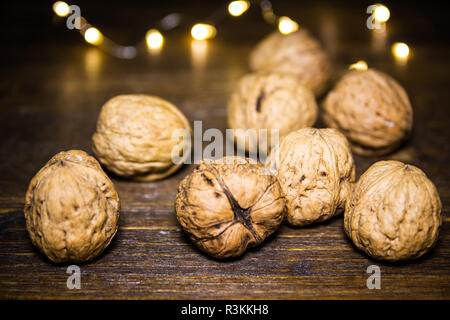 Walnuts on a wooden table with blurred lights in the background Stock Photo
