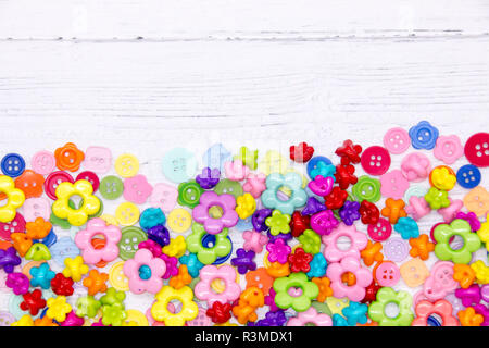 A collection of colourful sewing buttons and beads on a painted white wood background Stock Photo