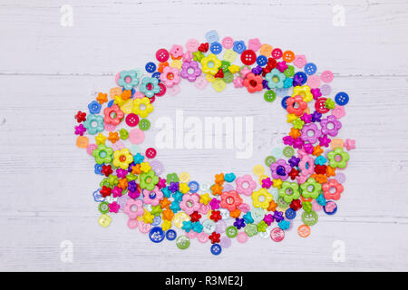 A collection of colourful sewing buttons and beads on a painted white wood background