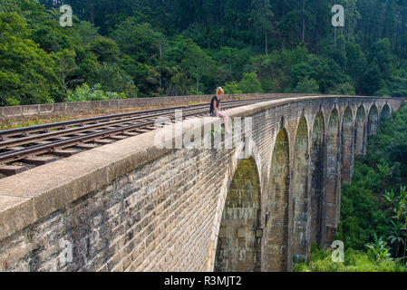 A young woman admiring the view from the Nine Arch Bridge in Ella, Sri Lanka Stock Photo