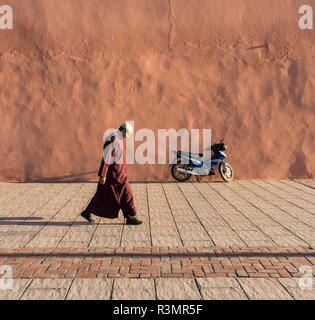 Man walks along red-orange city walls of Marrakech (Marrakesh), Morocco