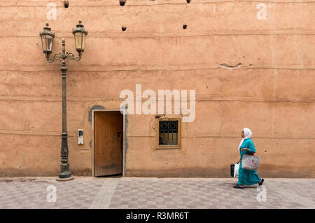Woman walks along clay walls of Badi Palace in Marrakech (Marrakesh), Morocco