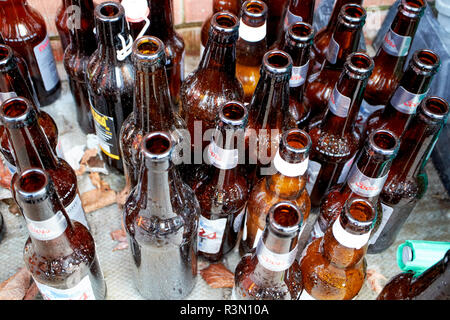 empty beer bottles left sitting on the pavement outside a house Stock Photo