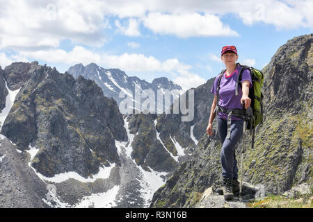 Climbing. Woman stands on edge of mountain peak. Outdoor activities Stock Photo
