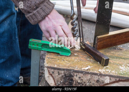 Drilling holes in a wooden seat to affix the legs. Stock Photo