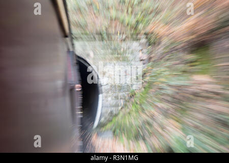 On board moving vintage train, view from window with fast train motion blur approaching tunnel. Concept: speed, movement, travelling fast. Stock Photo