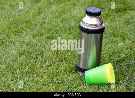 Thermos with a hot drink on mountain waterfall Stock Photo by