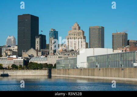 Canada, Quebec, Montreal. Old Port area city skyline view from St. Lawrence River. New cruise pier with Notre-Dame Basilica in the distance. Stock Photo