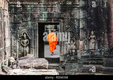 Siem Reap, Cambodia. Monk walks through a doorway among the ancient ruins and towers of the Bayon Temple in Preah Khan Stock Photo