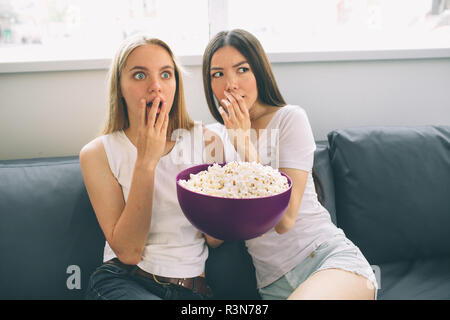 Women eating popcorn and watching tv Stock Photo