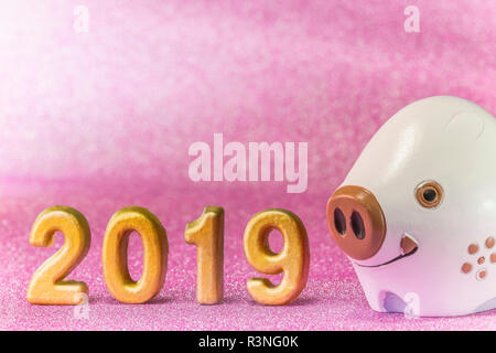 Pink glitter background for japanese New Year's Cards with cute animal figurine of boar or pig and handmade golden numbers of 2019 year. Stock Photo