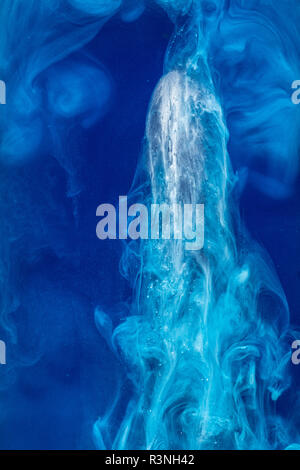 Abstract pattern falling into the water drop of blue ink - cyan ink dissolved in water on blue Stock Photo