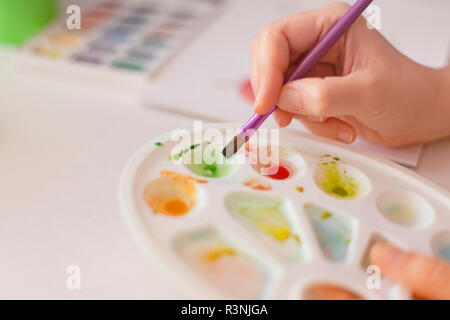 Person using watercolor paints with a brush. Shallow depth of field. Close up. Stock Photo
