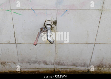 Water tap faucet with valve handle hinged on white tiles. Stock Photo