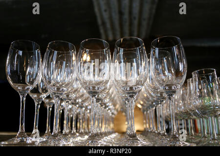 Group of bright white wine glasses on the table of the restaurant; cognac glasses on the other line on the left Stock Photo
