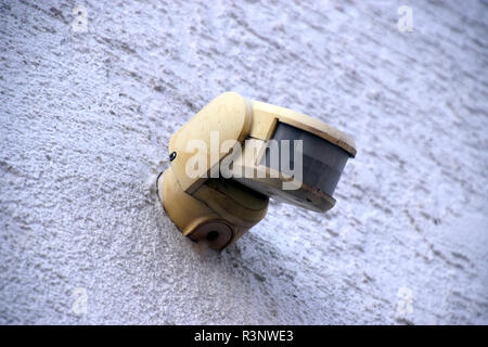 old and dirty motion detector on a house wall in the outdoor area, electric motion house light Stock Photo