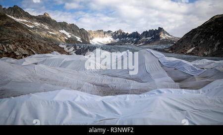 Climate | Albedo | Rhone: Huge fleece blankets cover parts of the Rhone Glacier in Switzerland in an attempt to stall the inevitable melting of the snow and ice. After a winter with record amounts of snow, most of it was gone when this image was taken on July 14th 2018, exposing the darker ice. While snow is a brilliant reflector of the energy from the sun, the darker ice absorbs the energy instead, accelerating the melting of the glacier. The color and darkness of glacier ice vary all over the world, depending on build-up of pollution, age of the ice, particles picked up by the ice and by mic Stock Photo