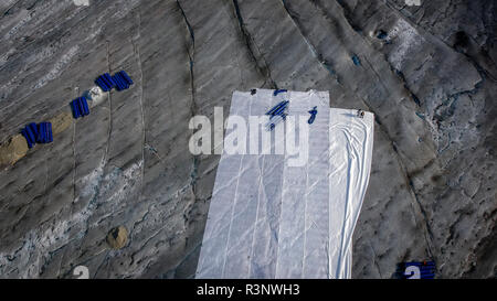 Climate | Albedo | Rhone: Huge fleece blankets cover parts of the Rhone Glacier in Switzerland in an attempt to stall the inevitable melting of the snow and ice. After a winter with record amounts of snow, most of it was gone when this image was taken on July 14th 2018, exposing the darker ice. While snow is a brilliant reflector of the energy from the sun, the darker ice absorbs the energy instead, accelerating the melting of the glacier. The color and darkness of glacier ice vary all over the world, depending on build-up of pollution, age of the ice, particles picked up by the ice and by mic Stock Photo