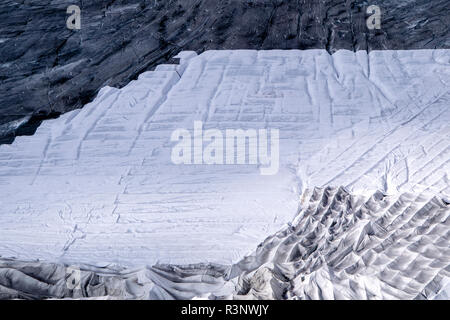 Climate | Albedo | Rhone: Huge fleece blankets cover parts of the Rhone Glacier in Switzerland in an attempt to stall the inevitable melting of the snow and ice. After a winter with record amounts of snow, most of it was gone when this image was taken on July 14th 2018, exposing the darker ice. While snow is a brilliant reflector of the energy from the sun, the darker ice absorbs the energy instead, accelerating the melting of the glacier. The color and darkness of glacier ice vary all over the world, depending on build-up of pollution, age of the ice, particles picked up by the ice and by mic Stock Photo