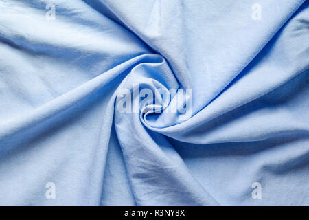 Twisted in the center cloth swatch of light blue fabric for shirts. Blank wrinkled textile background. Stock Photo