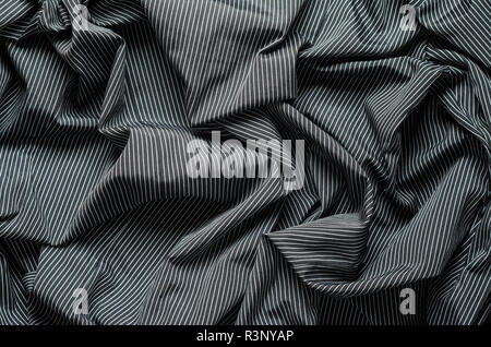 Wrinkled texture of black cloth with narrow white vertical lines. Crumplet backdrop textile background Stock Photo