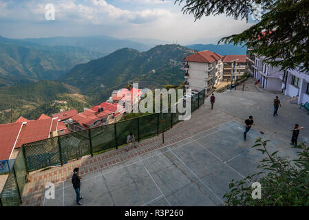 Youngsters playing a game of cricket with the Himalayan foothills in the backdrop in Kasumpti, Shimla, Himachal Pradesh, India Stock Photo