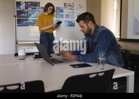 Executive using mobile phone in office Stock Photo