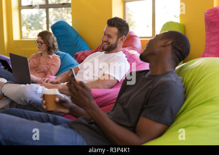 Business executives talking with each other while sitting on bean bag Stock Photo