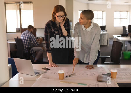 Business executives discussing over blueprint on table Stock Photo