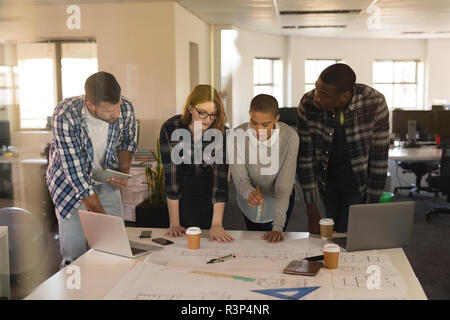 Business executives discussing over blueprint on table Stock Photo