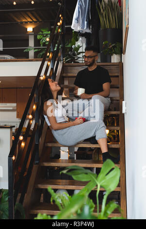 Couple interacting with each other while having coffee in stairs Stock Photo