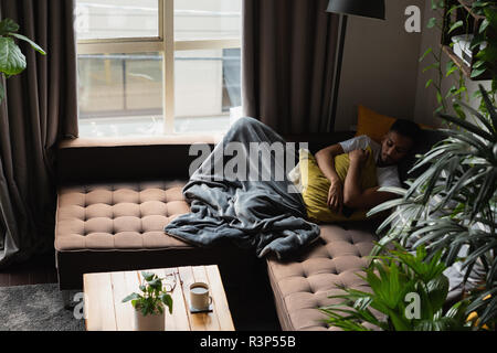 Man sleeping on sofa in living room Stock Photo