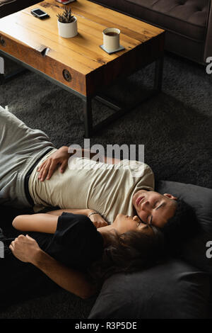 Couple sleeping on floor in living room Stock Photo