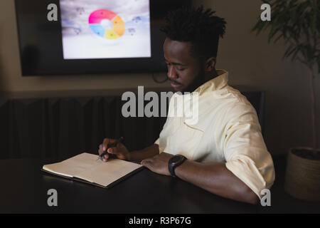 Male executive writing on a diary in conference room Stock Photo