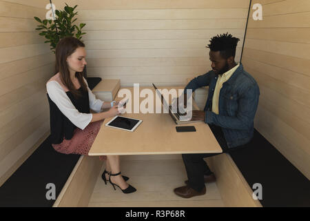 Business colleagues using mobile phone and laptop Stock Photo