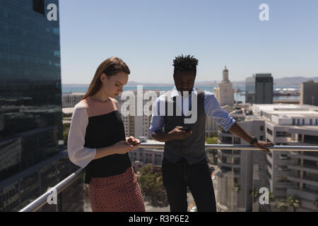 Business colleagues using mobile phone at terrace Stock Photo