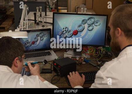 Robotics engineers working at desk in warehouse Stock Photo