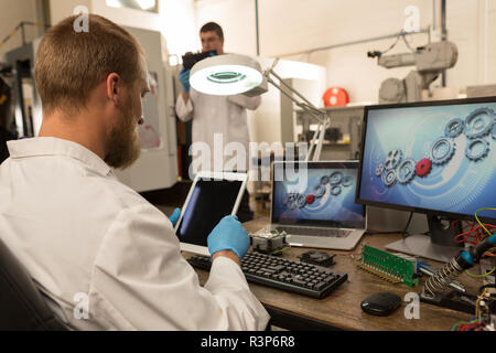 Robotics engineer using digital tablet at desk Stock Photo