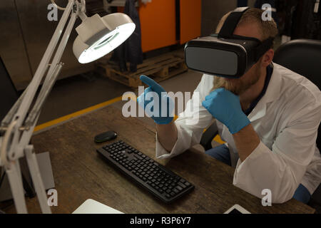 Robotics engineer using virtual reality headset at desk Stock Photo
