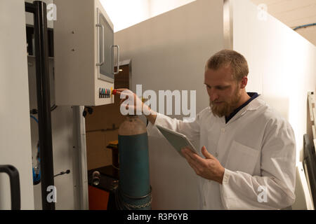 Robotics engineer using digital tablet while controlling control panel Stock Photo