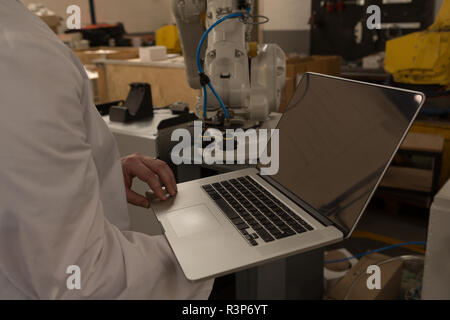 Robotics engineer using laptop in warehouse Stock Photo