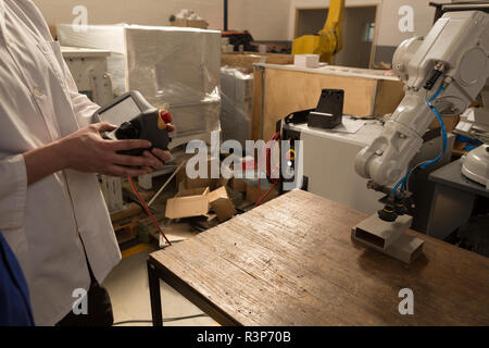 Robotic engineers operating robotic machine with remote control Stock Photo