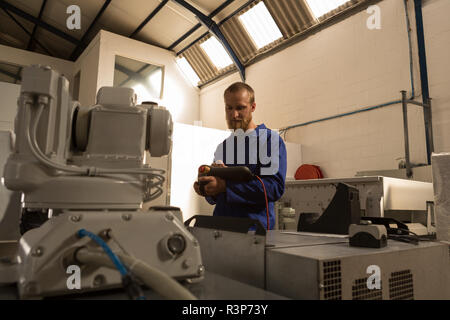 Robotic engineers operating robotic machine with remote control Stock Photo