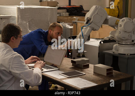 Robotic engineers examining robotic machine Stock Photo