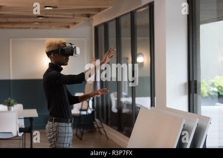 Businessman using virtual reality headset in office Stock Photo