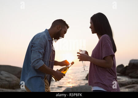 Man opening champagne bottle near sea side Stock Photo