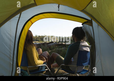 Couple relaxing near tent in the forest Stock Photo
