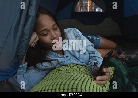 Woman using mobile phone in tent Stock Photo