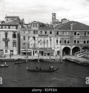1950s, historical, a view of a canal and buildings in Venice, including a gondola on the water, the traditional symbol of the Italian city. The capital of the Veneto region is situated on a group of 118 small islands seperated by canals and linked by over 400 bridges. Stock Photo