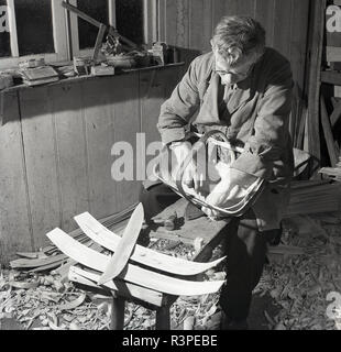 1950s, historical, a male craftsman making by hand a wooden basket in his workshop, England, UK. Basket weaving is an old, sacred tradition and was once an important skill in an age when containers were an indispensbale part of life. Stock Photo